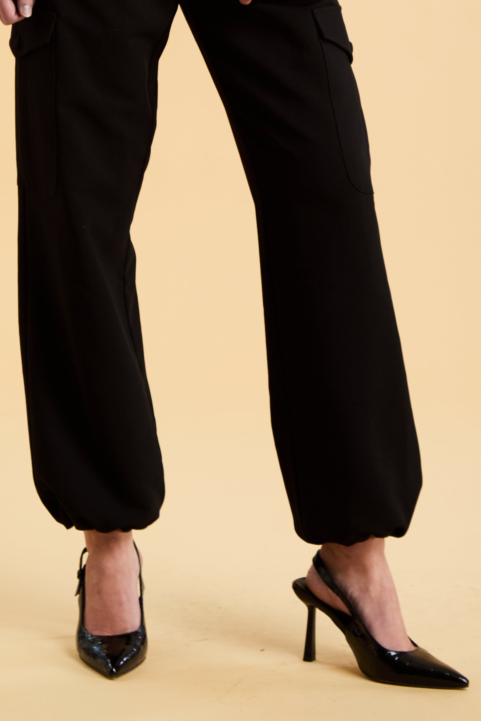Black pants worn by a person on a beige background
