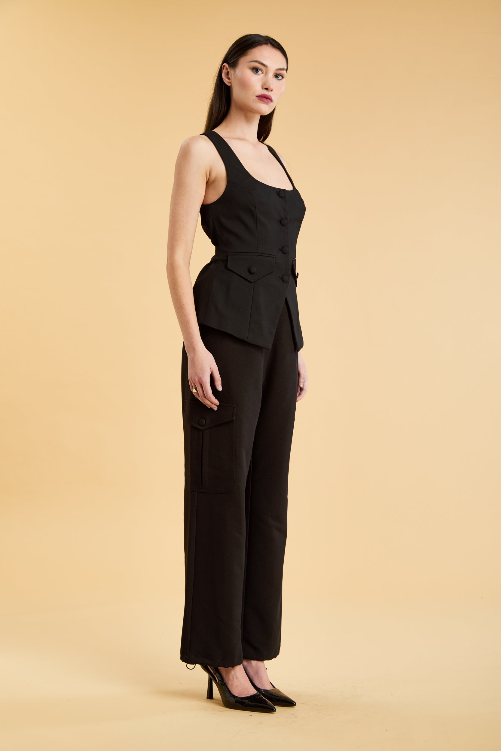 Woman wearing a white top and black cargo pants on a beige background