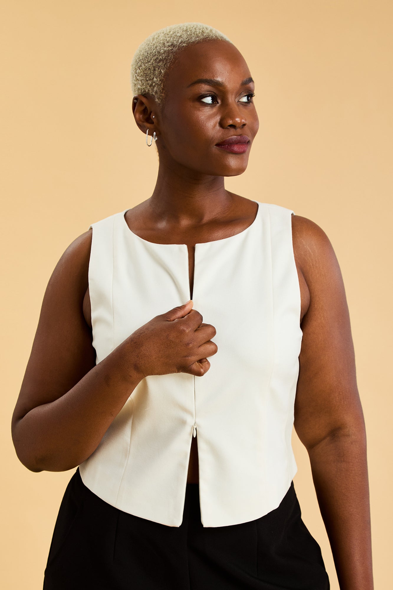 Woman wearing a white sleeveless top against a beige background