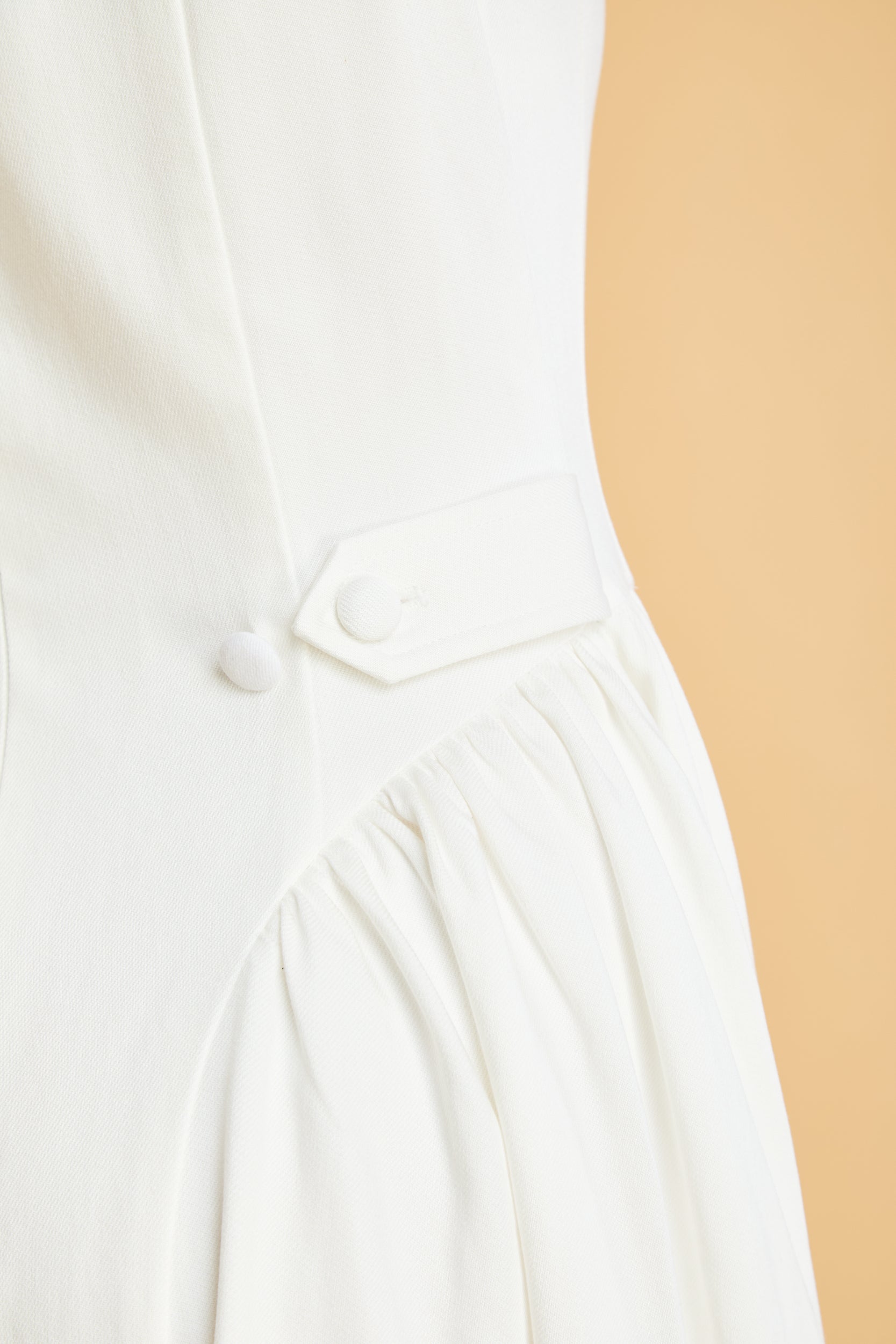 Close-up of a White dress with buttons on a beige background