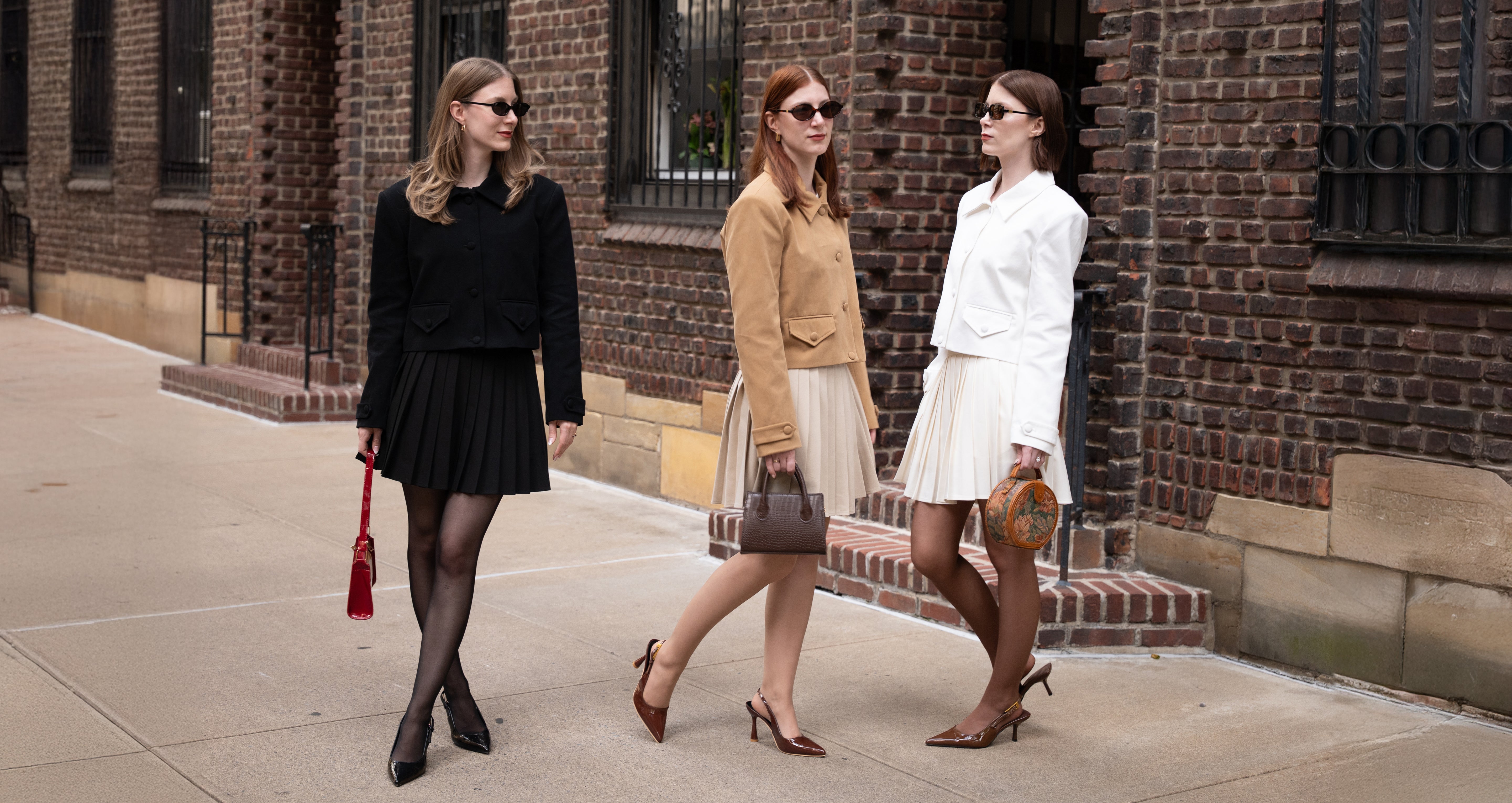 Three women (The Levesque Triplets) walking on a sidewalk in front of a brick building wearing Triplicity Clothing.