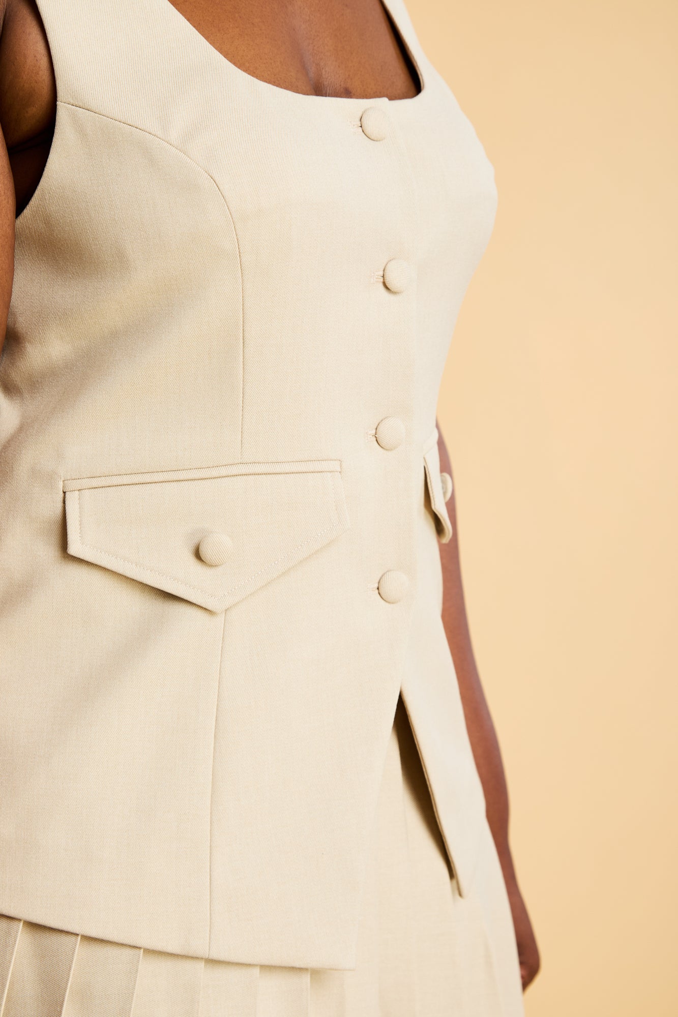 Oat colored Triplicity Georgiana Vest top sleeveless dress with button details on a beige background