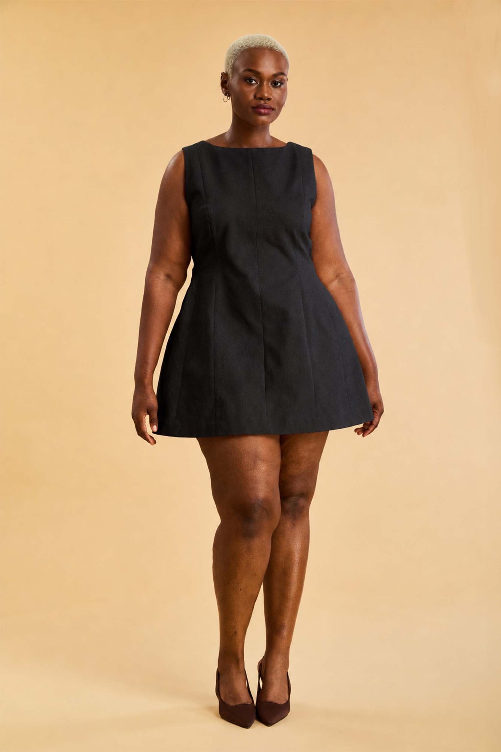 Woman wearing a black sleeveless dress against a beige background