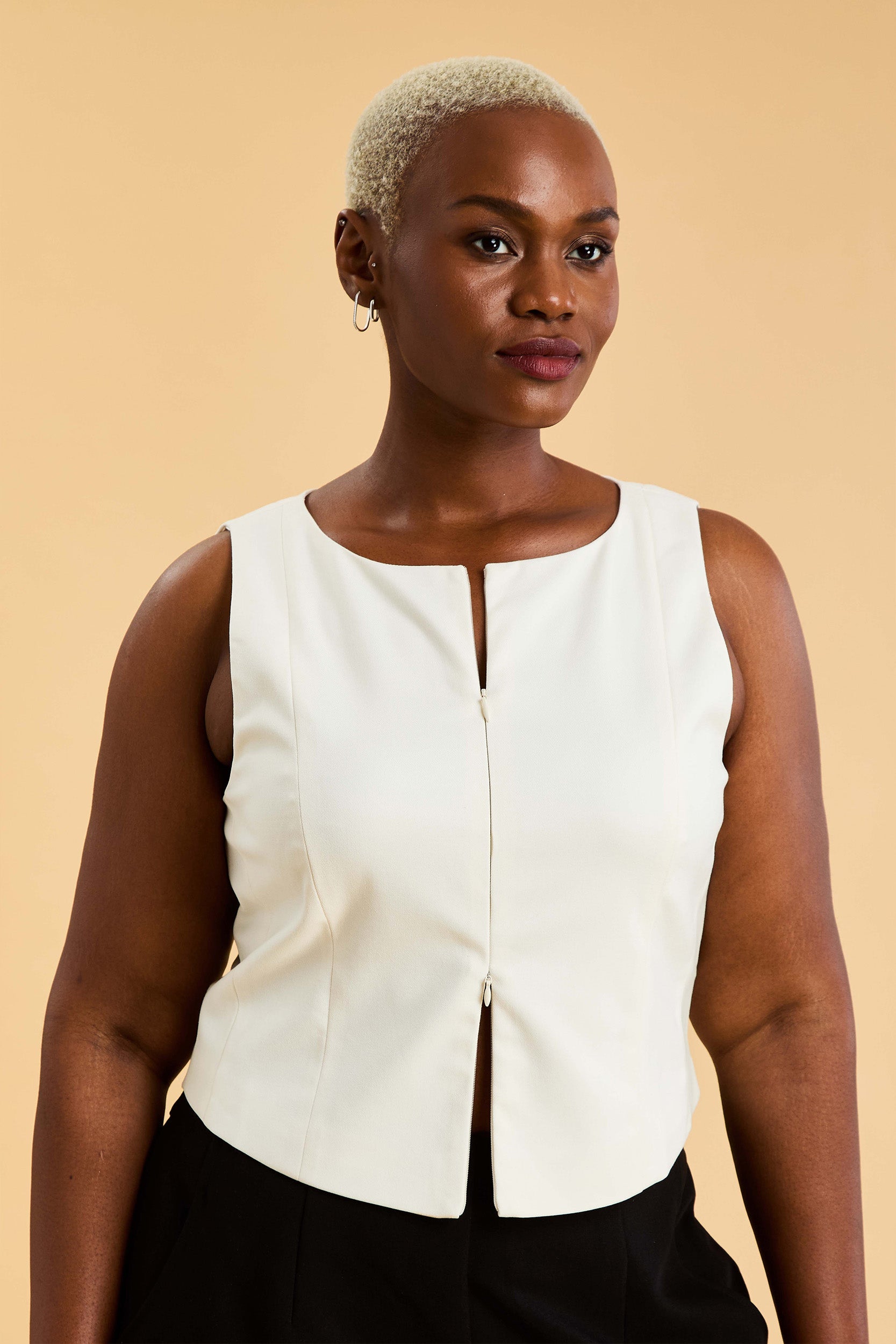 woman wearing a Black double ended zipper top on a beige background close up