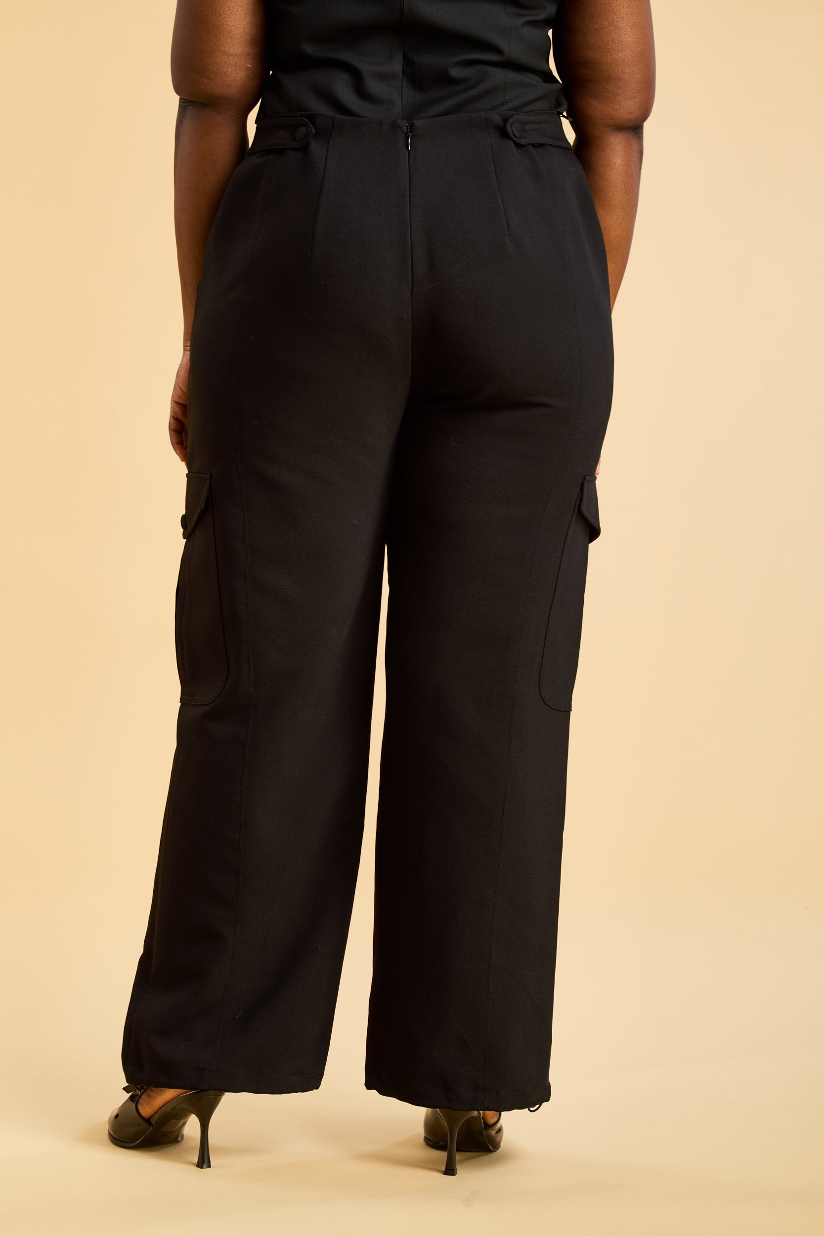 Person wearing black wide-leg pants on a beige background