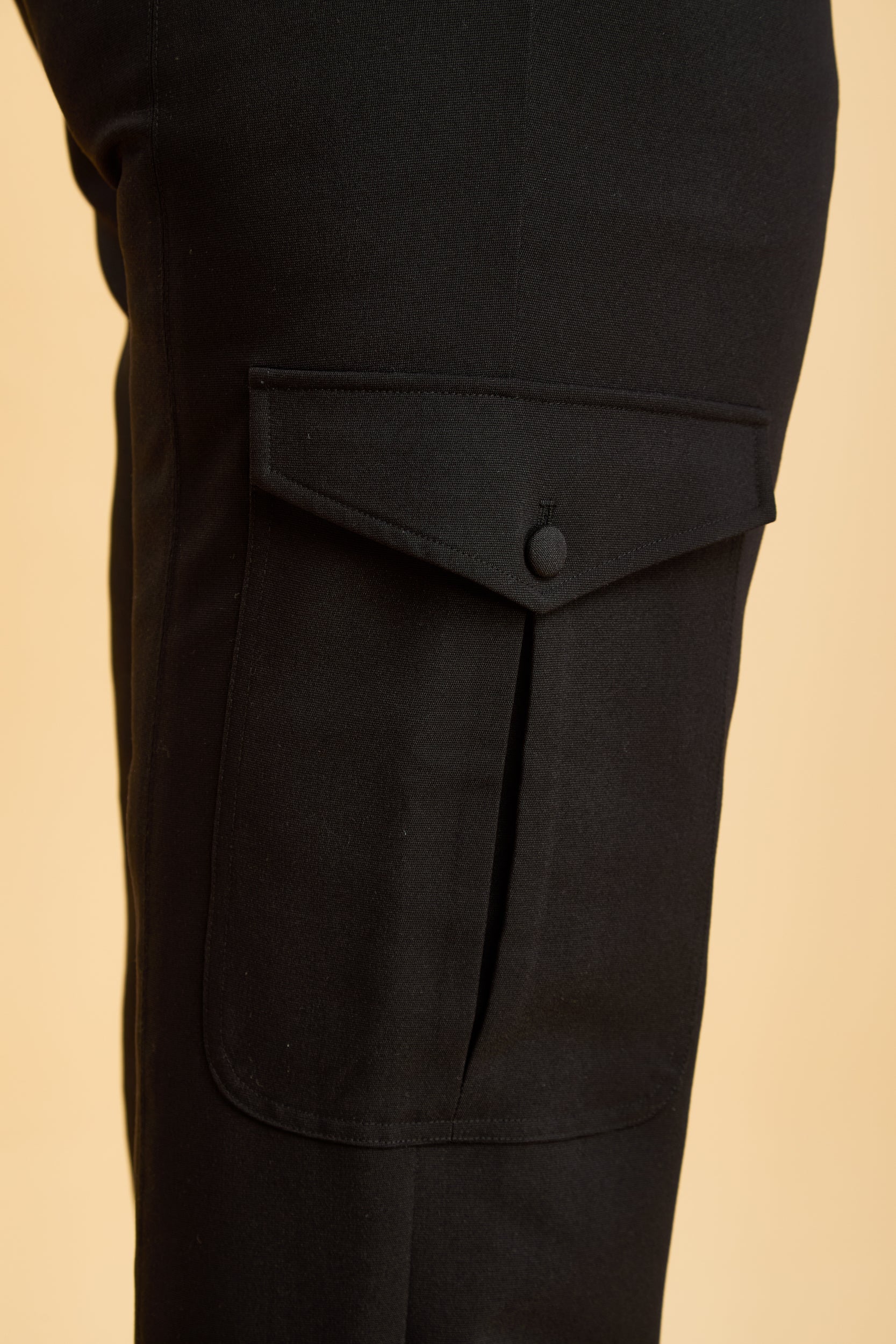 Close-up of black pants with a cargo pocket on a beige background