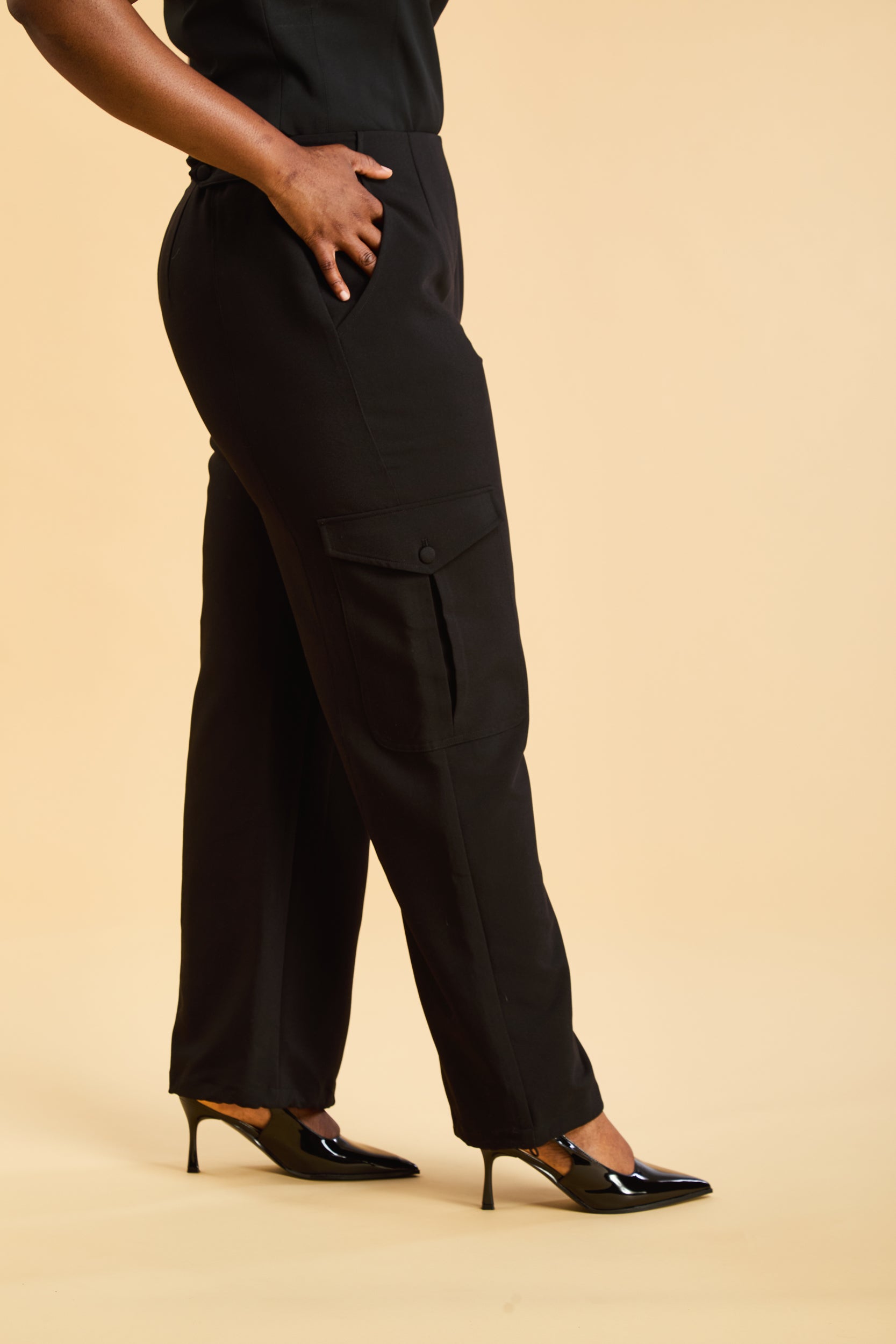 Person wearing black cargo pants on a beige background