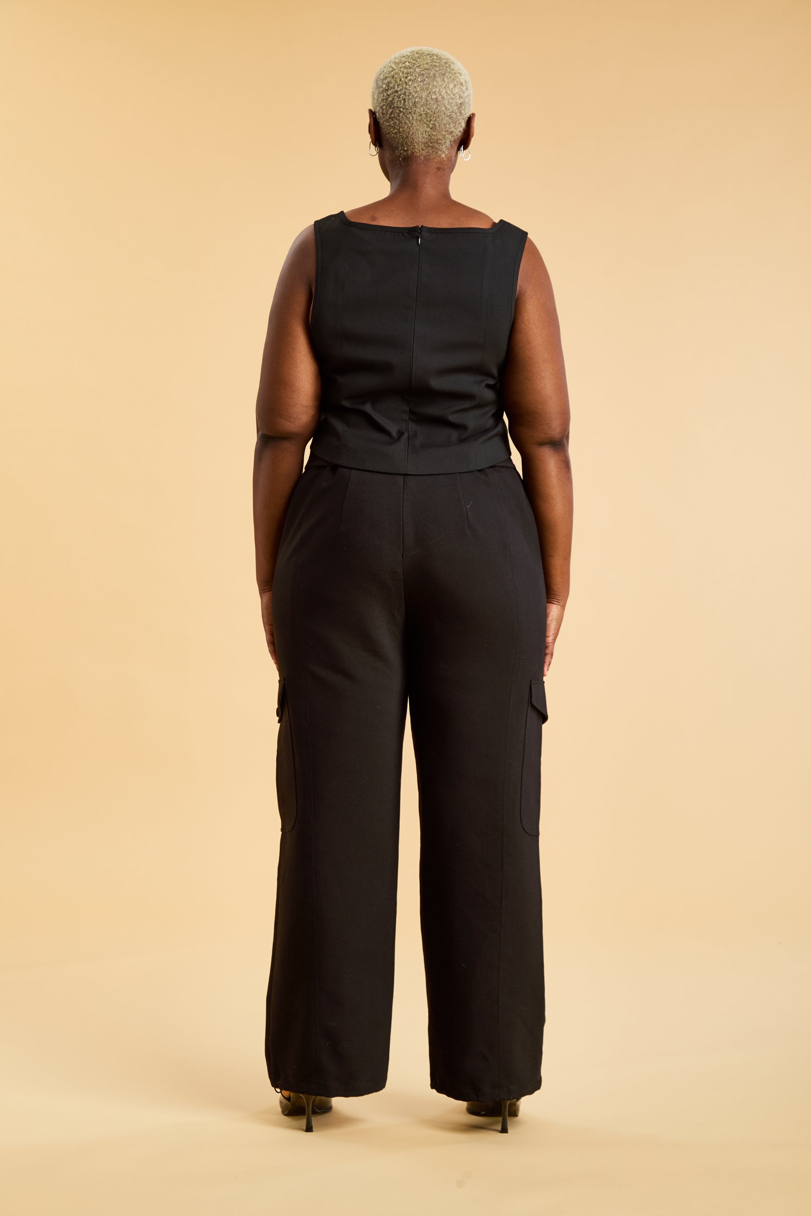 Person wearing black cargo pants on a beige background