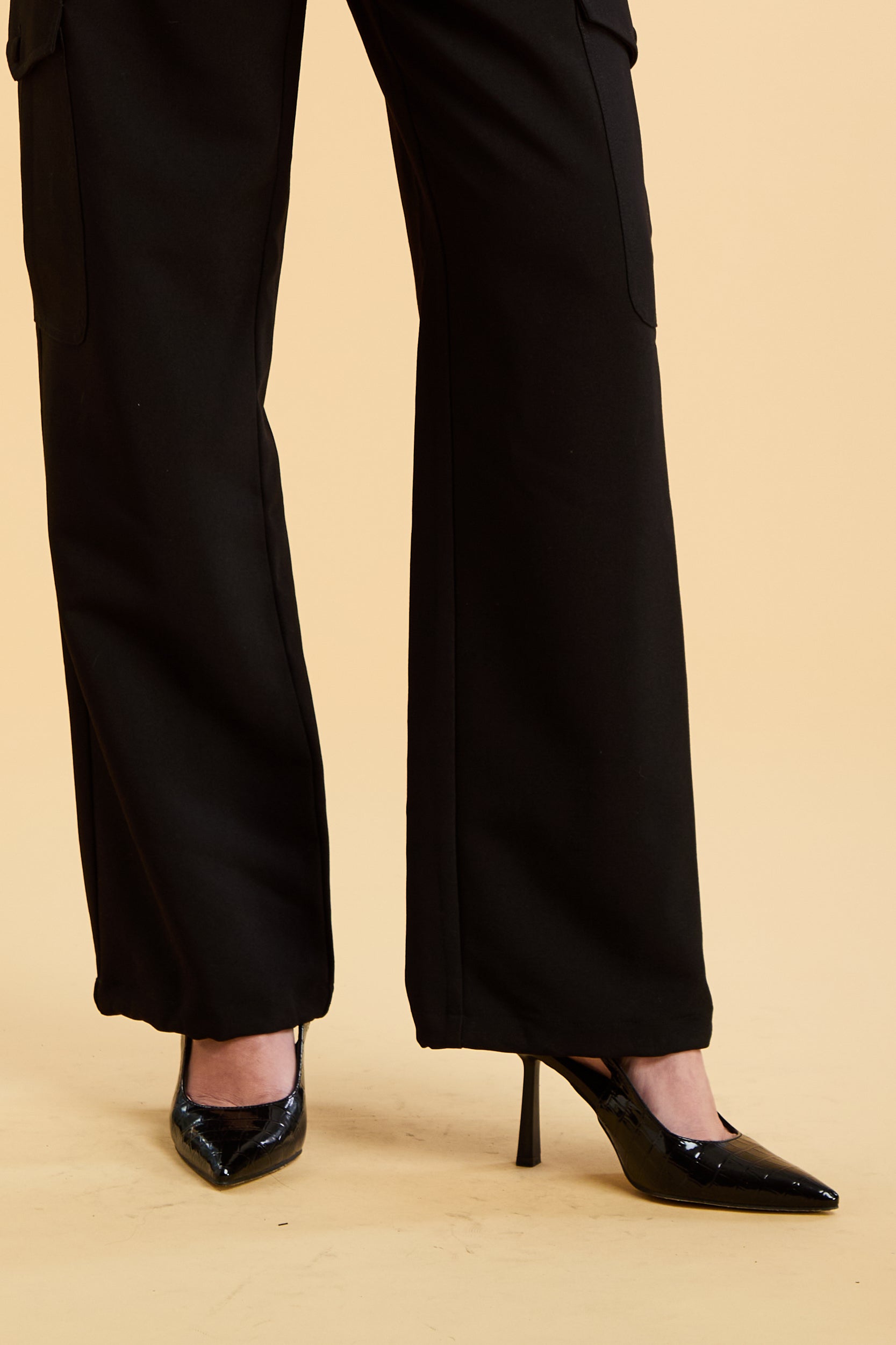 Black pants and high-heeled shoes on a beige background