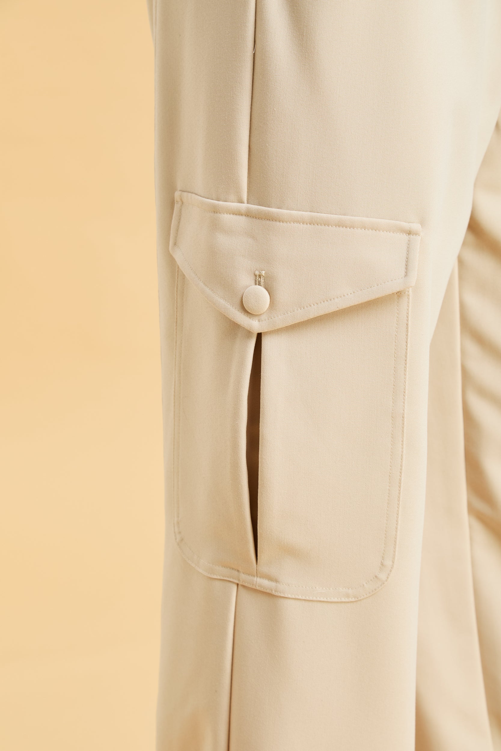 Beige pants with a pocket and button on a beige background