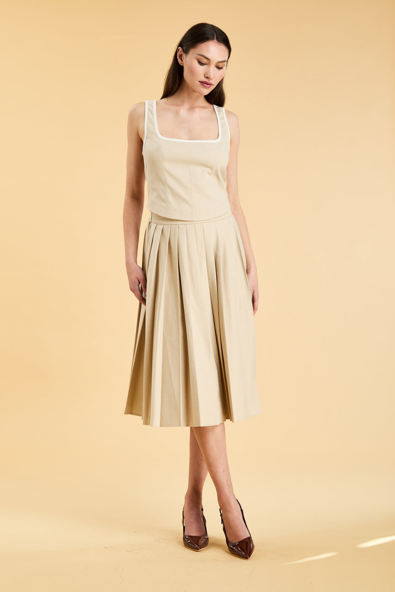 Woman wearing a light yellow dress against a beige background