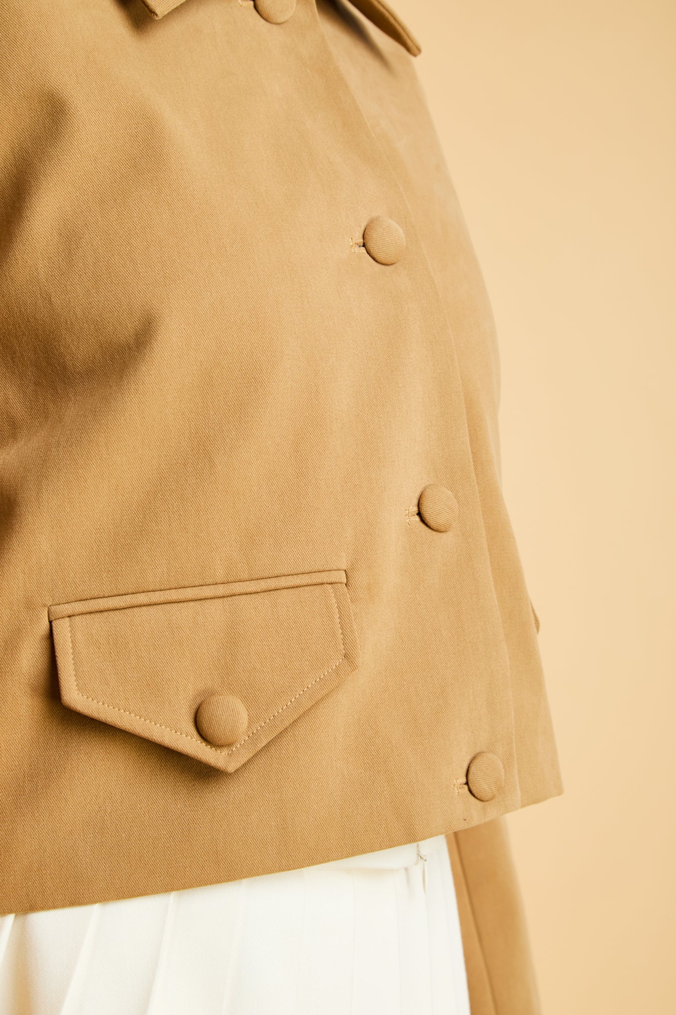 Close-up of a Camel colored jacket coat with buttons on a beige background