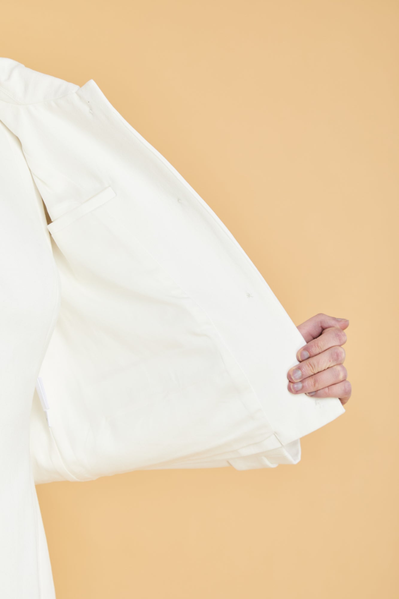 White fabric held by a hand against a beige background