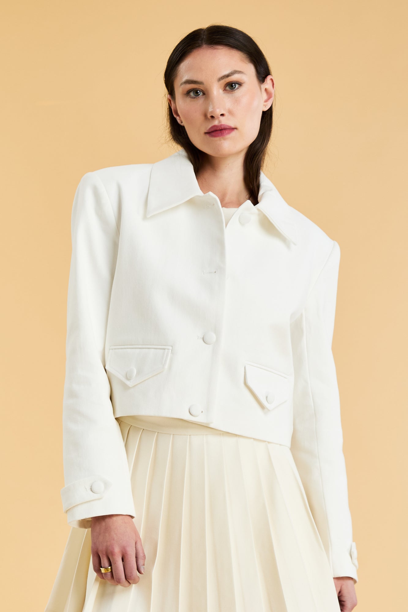 Woman wearing a White Triplicity collared tailored jacket against a beige background front view close up