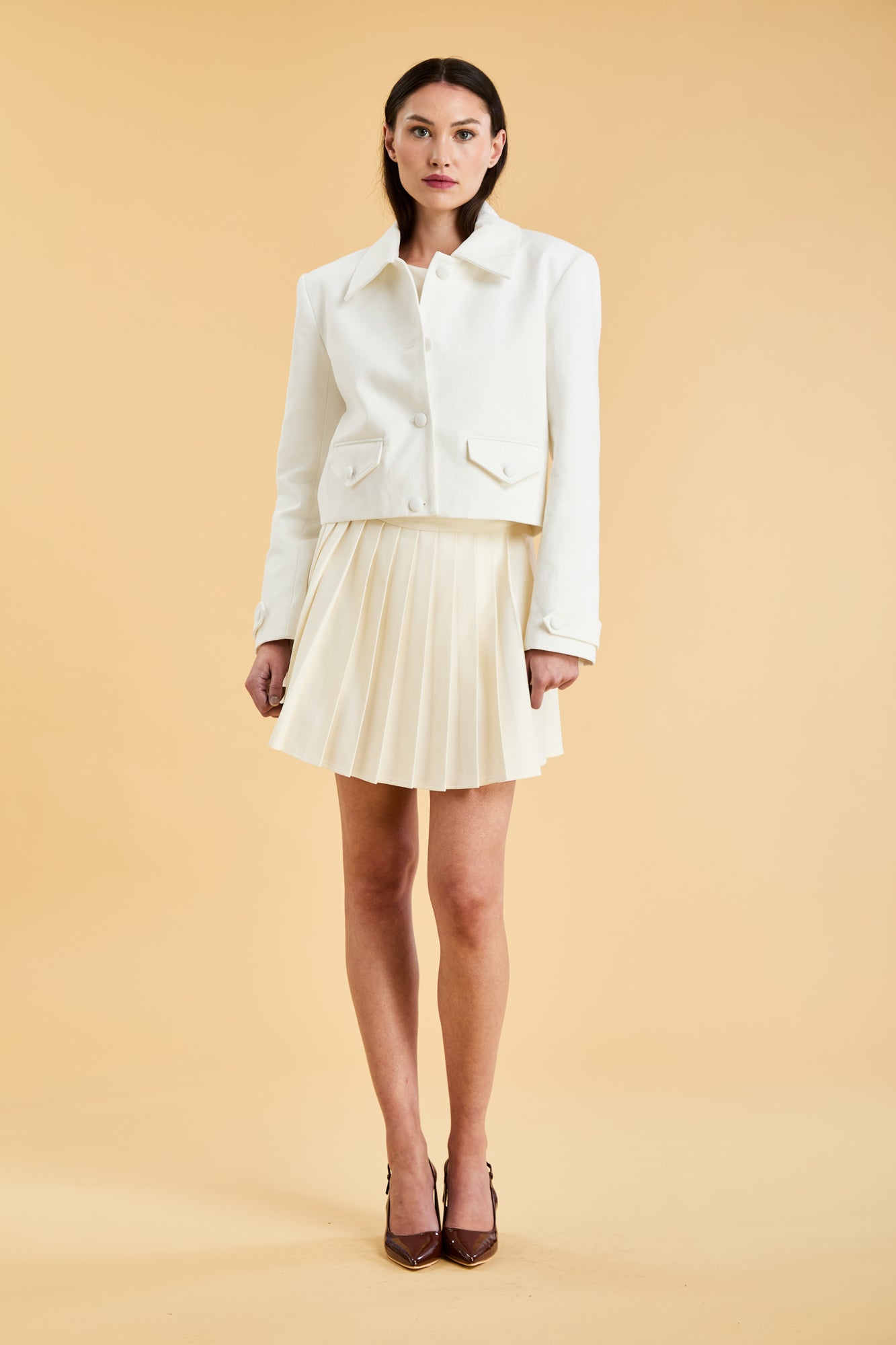Woman wearing a White Triplicity collared tailored jacket against a beige background front view full body