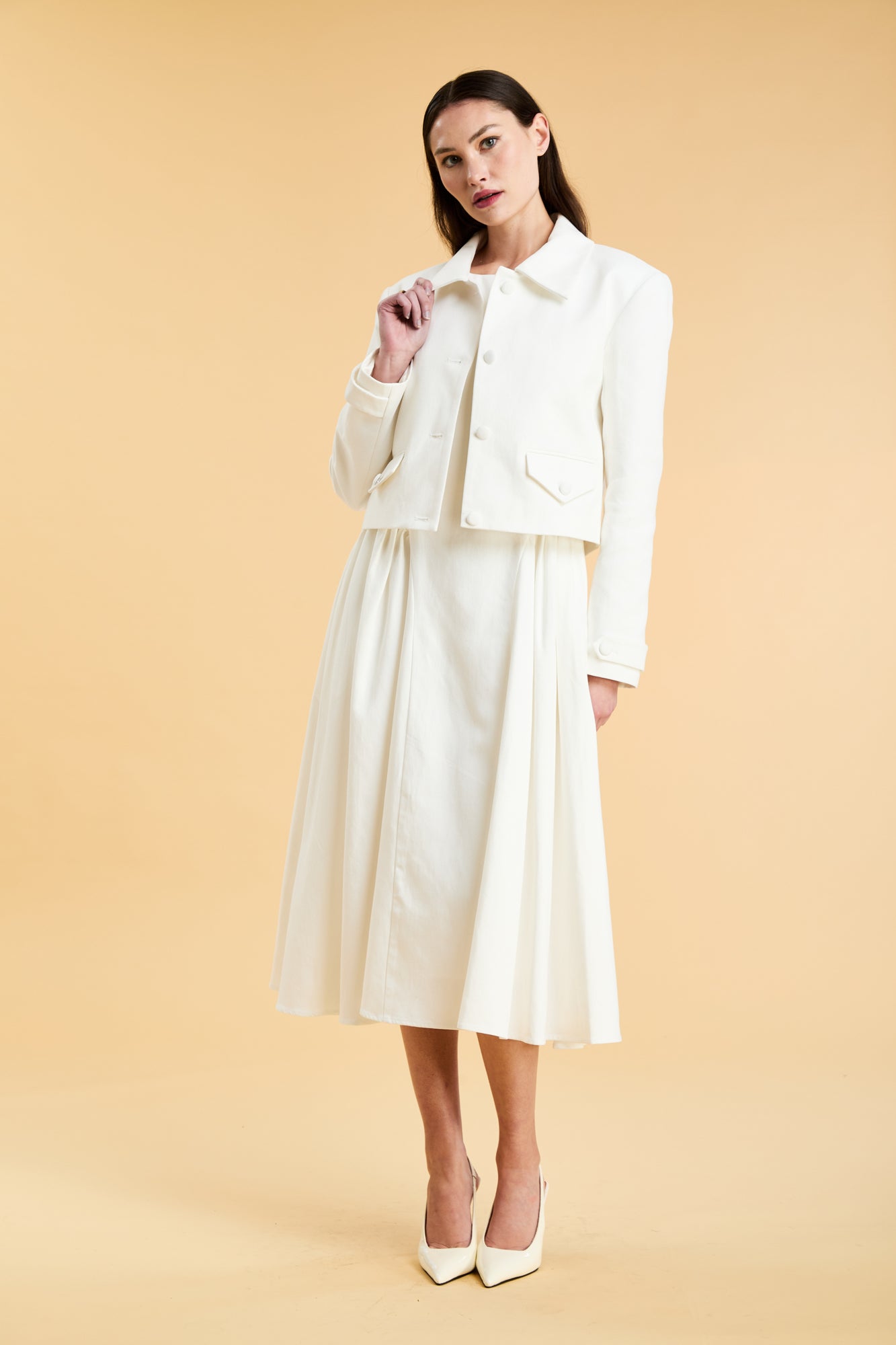 Woman wearing a White Triplicity collared tailored jacket on top of a White Triplicity Eleanor Midi Dress on a beige background front view full body