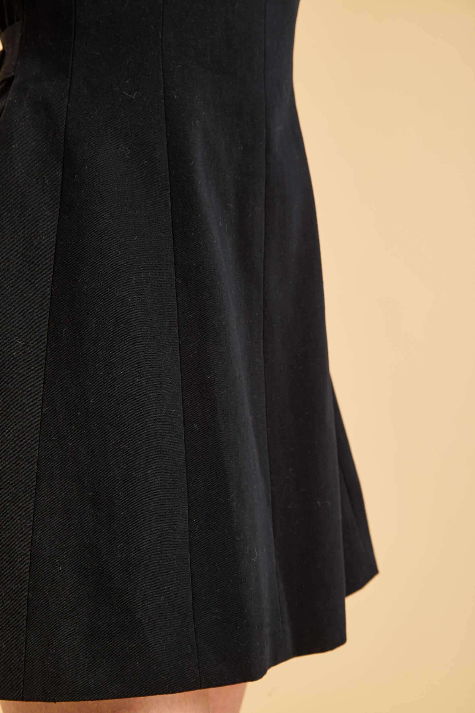Close up view of the Triplicity Louise Sleeveless Mini Dress to show detail seams on bottom of dress