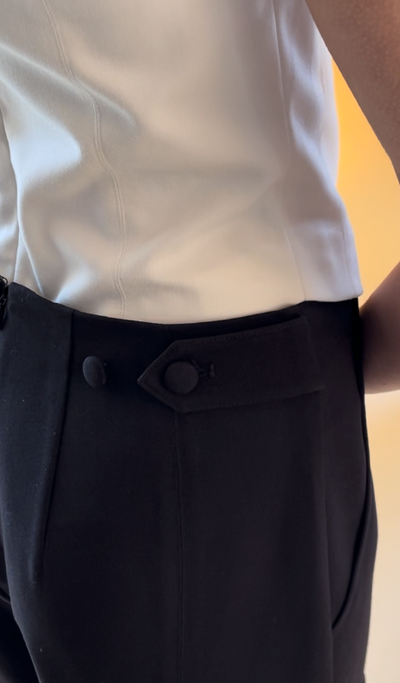 close up of the Adelaide black pants with adjustable waist tab with buttons and hands closing the tab