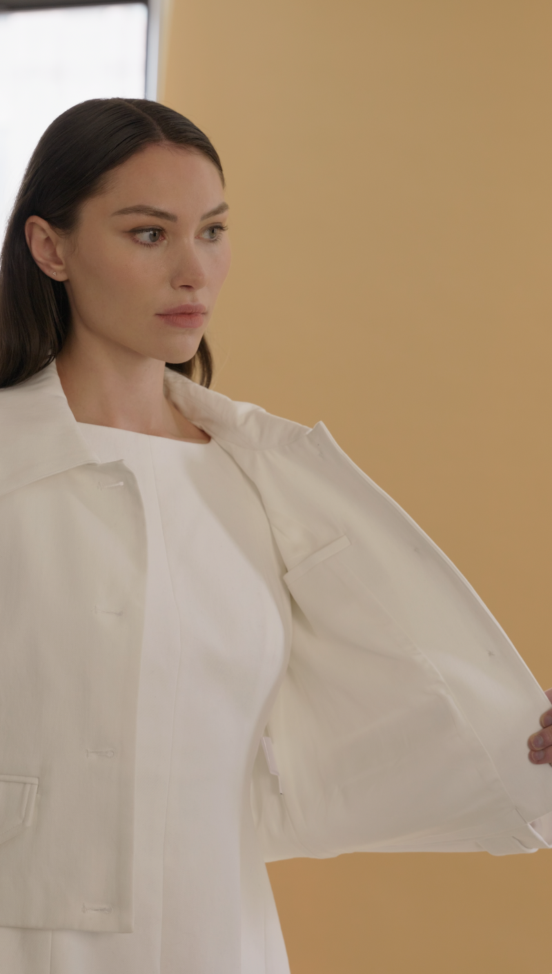 close up of a woman wearing the Charlotte White jacket holding it open showing the interior pocket