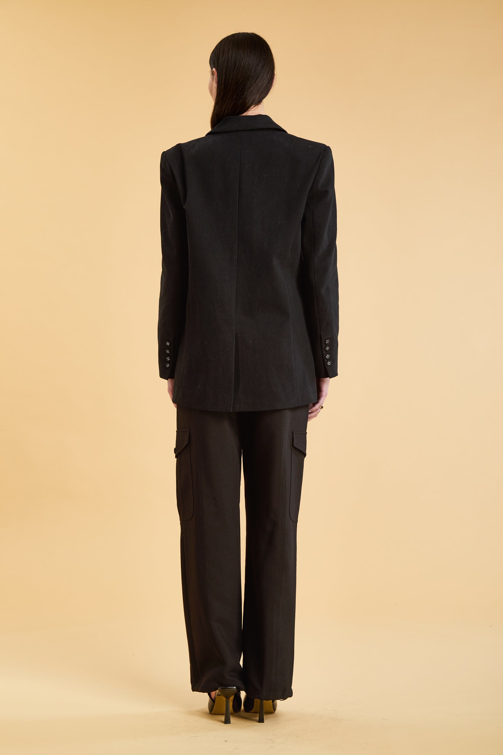 Woman wearing a Black oversized triplicity blazer over a white top on a beige background front view back view