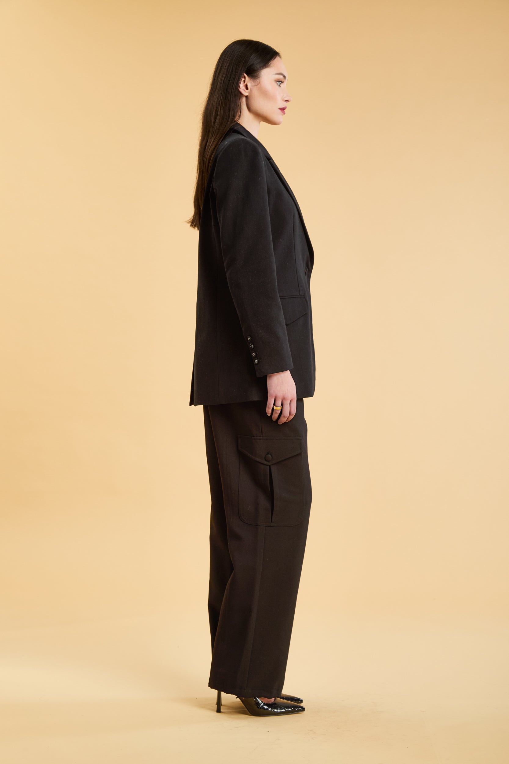 Woman wearing a Black oversized triplicity blazer over a white top on a beige background front view side view